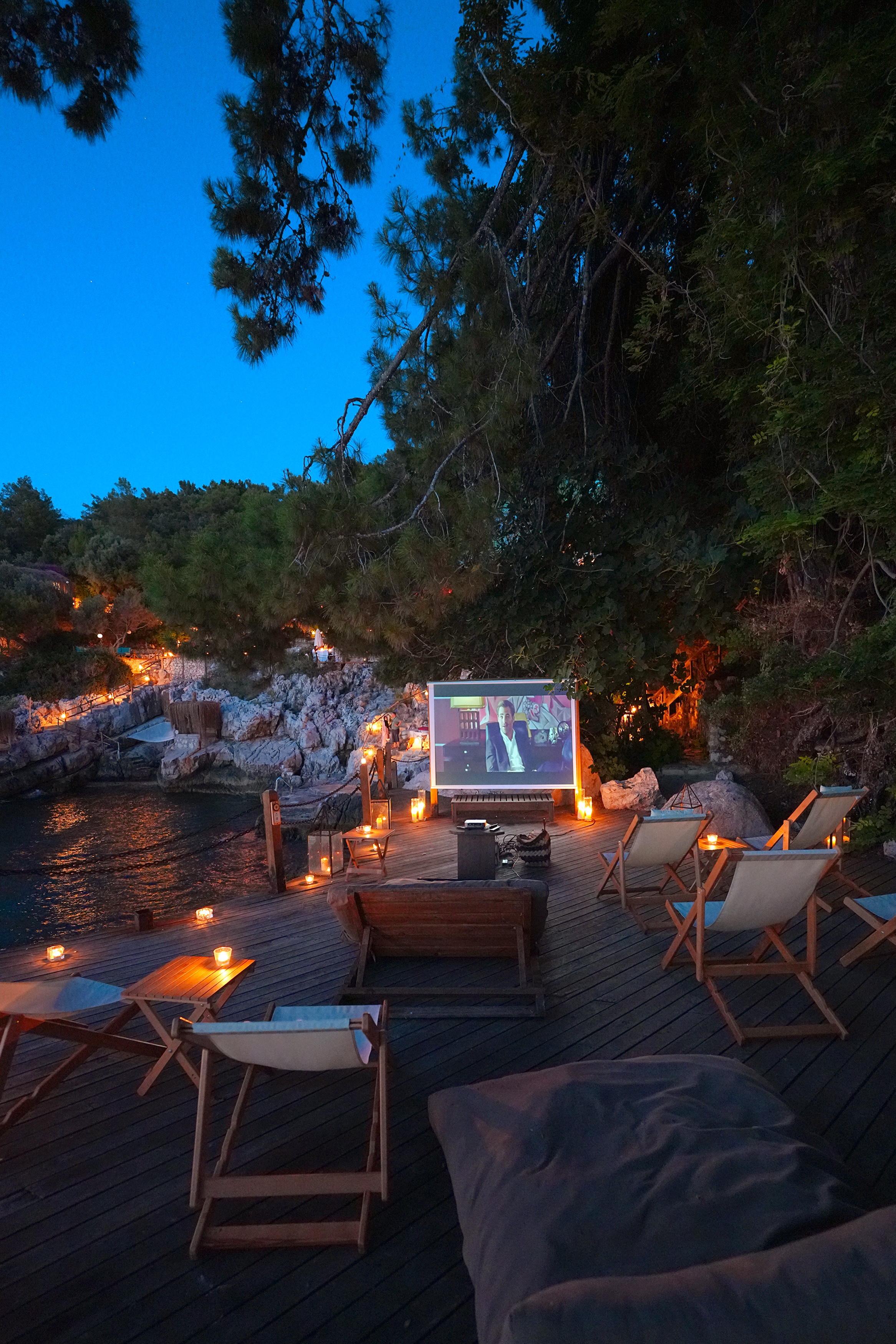 An outdoor screen and lantern-lit seating on a deck at night